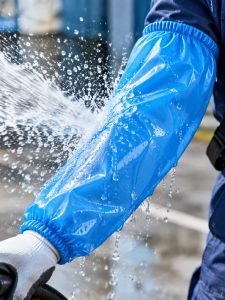 Blue TPU waterproof oversleeve deflecting a spray of wash water on a food plant floor
