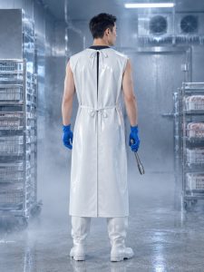 Worker seen from behind wearing a white back-tied TPU sleeveless smock gown in a misty cold room